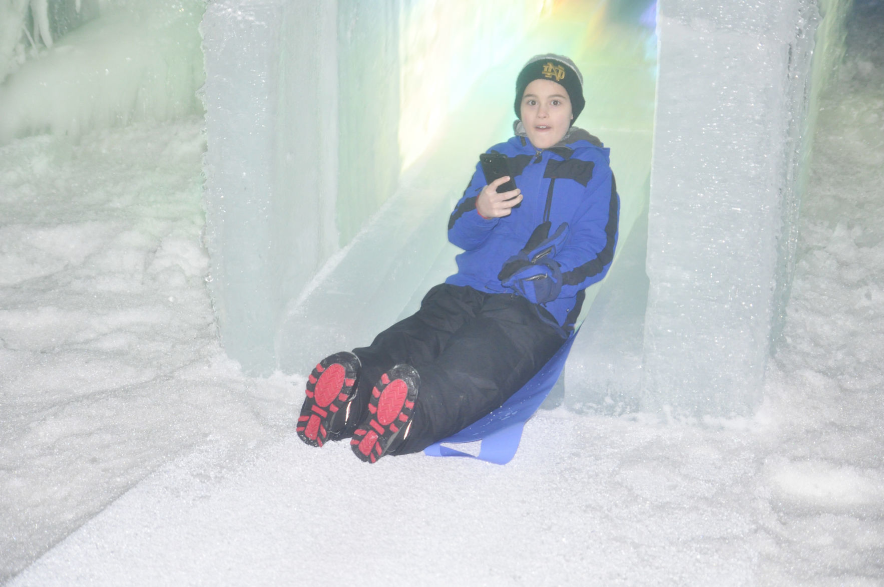 Boy uses cellphone on ice castle slide